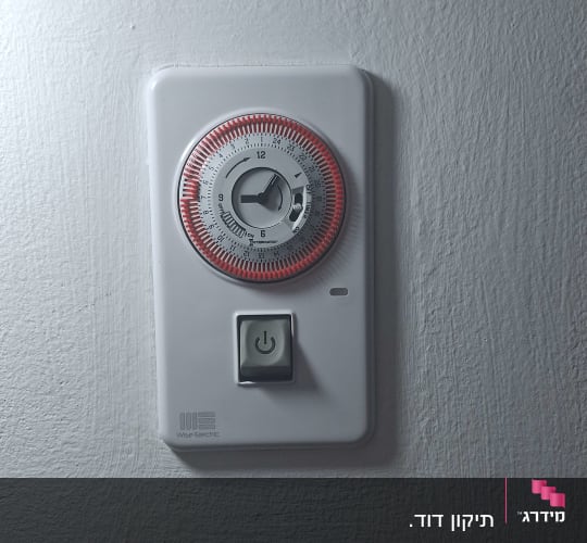 טיימר חשמלי על קיר עם כפתור הפעלה